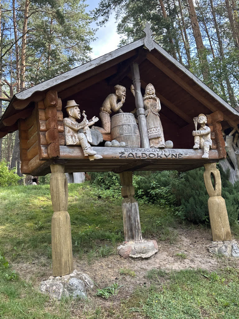 Medinių skulptūrų grupė po mediniu stogeliu