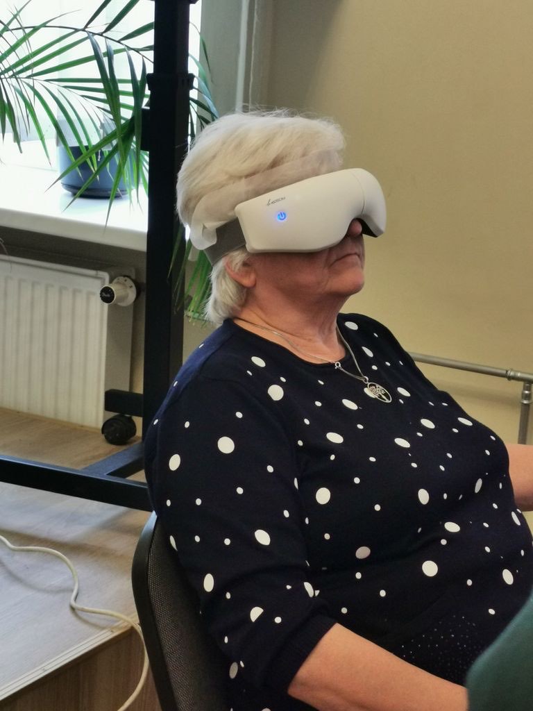 Moteris su virtualios realybės akiniais atsipalaidavusi sėdi fotelyje